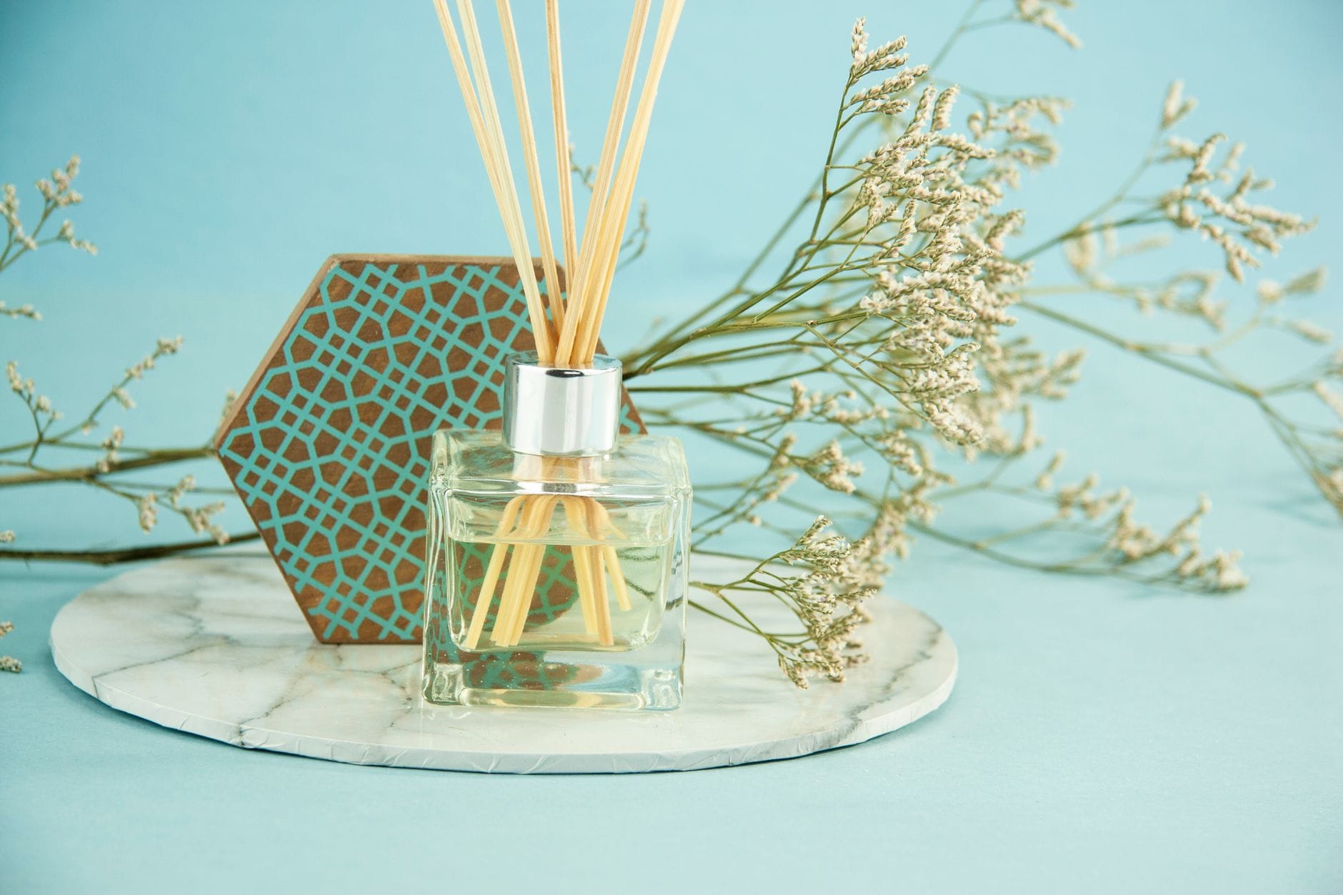 Reed diffuser and amber glass bottle on a wooden bathroom shelf