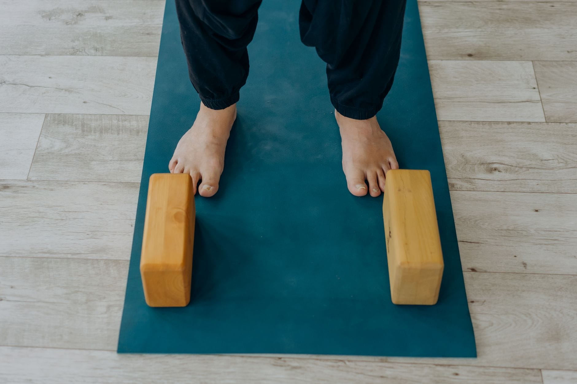 a single wooden yoga block resting on a bamboo mat
