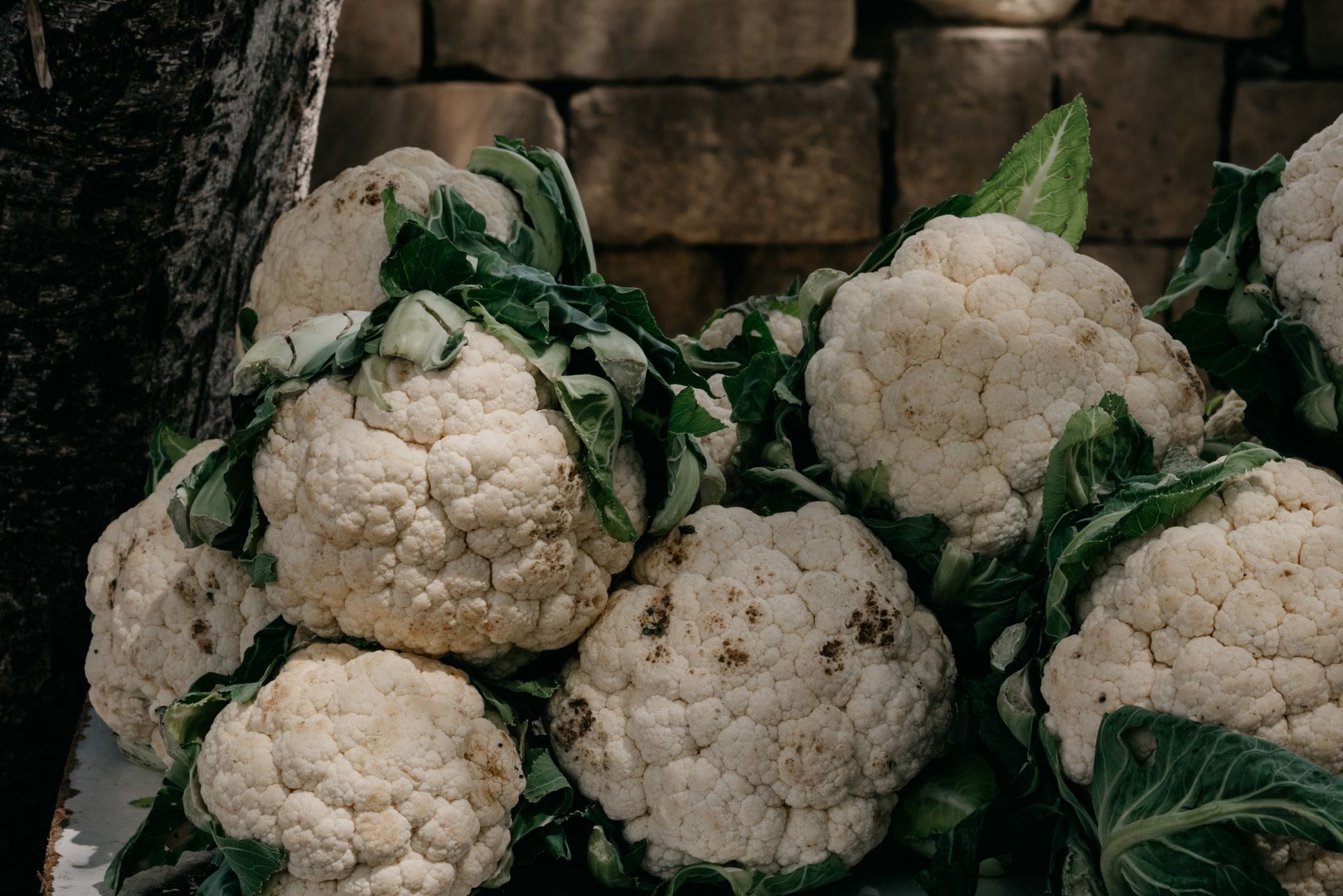 Whole raw cauliflower and green cabbage on a wooden board