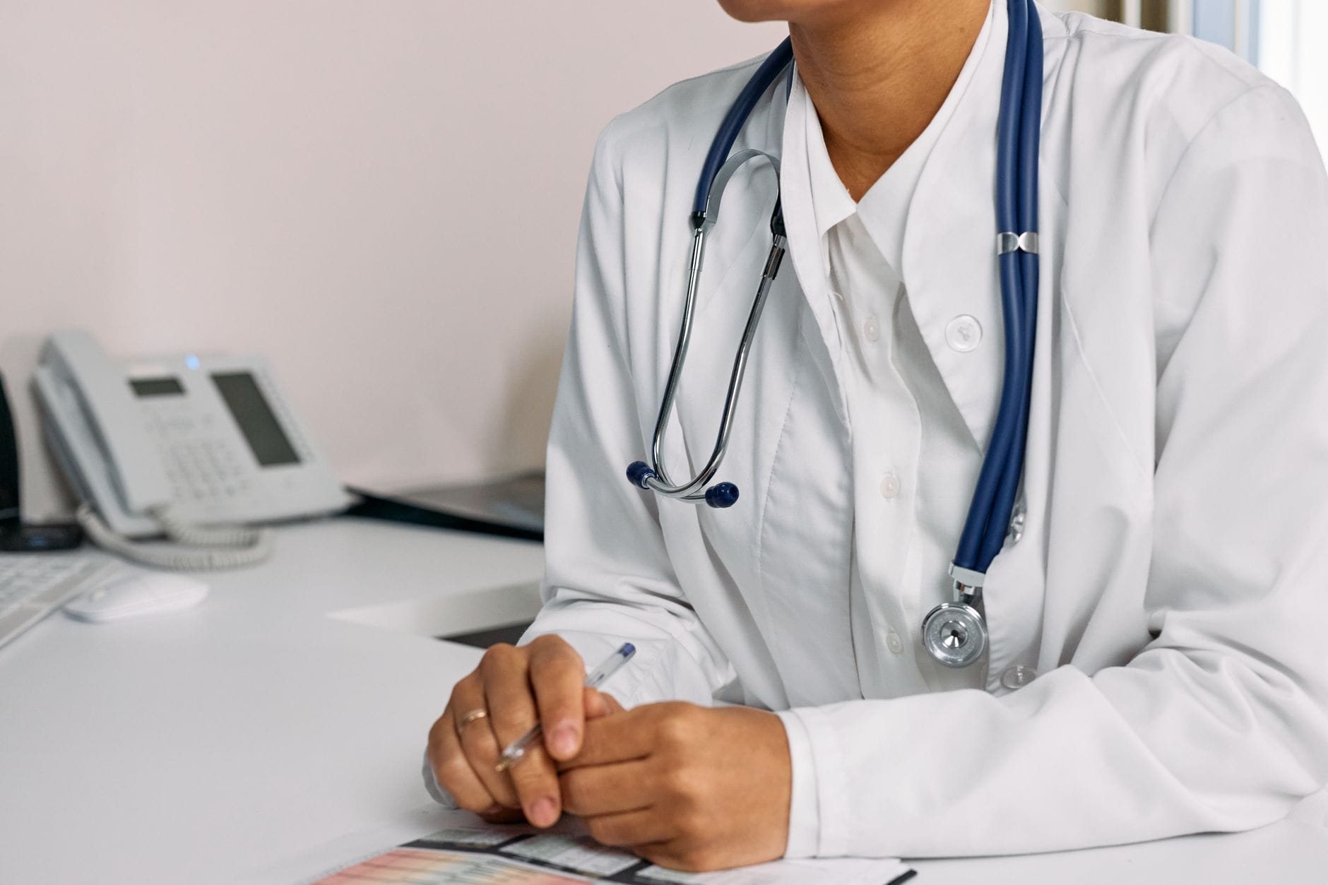 A stethoscope resting on a wooden surface beside a red heart shape
