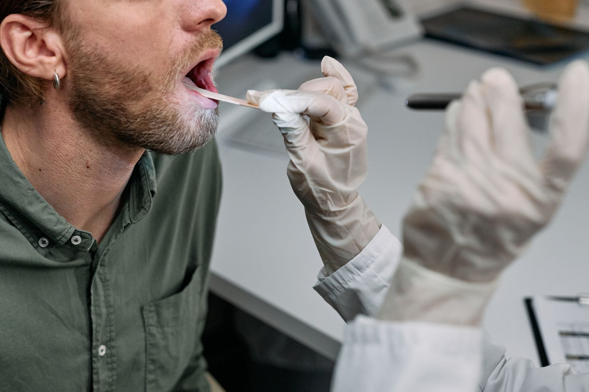 a doctor in a white coat examining a patient's open mouth