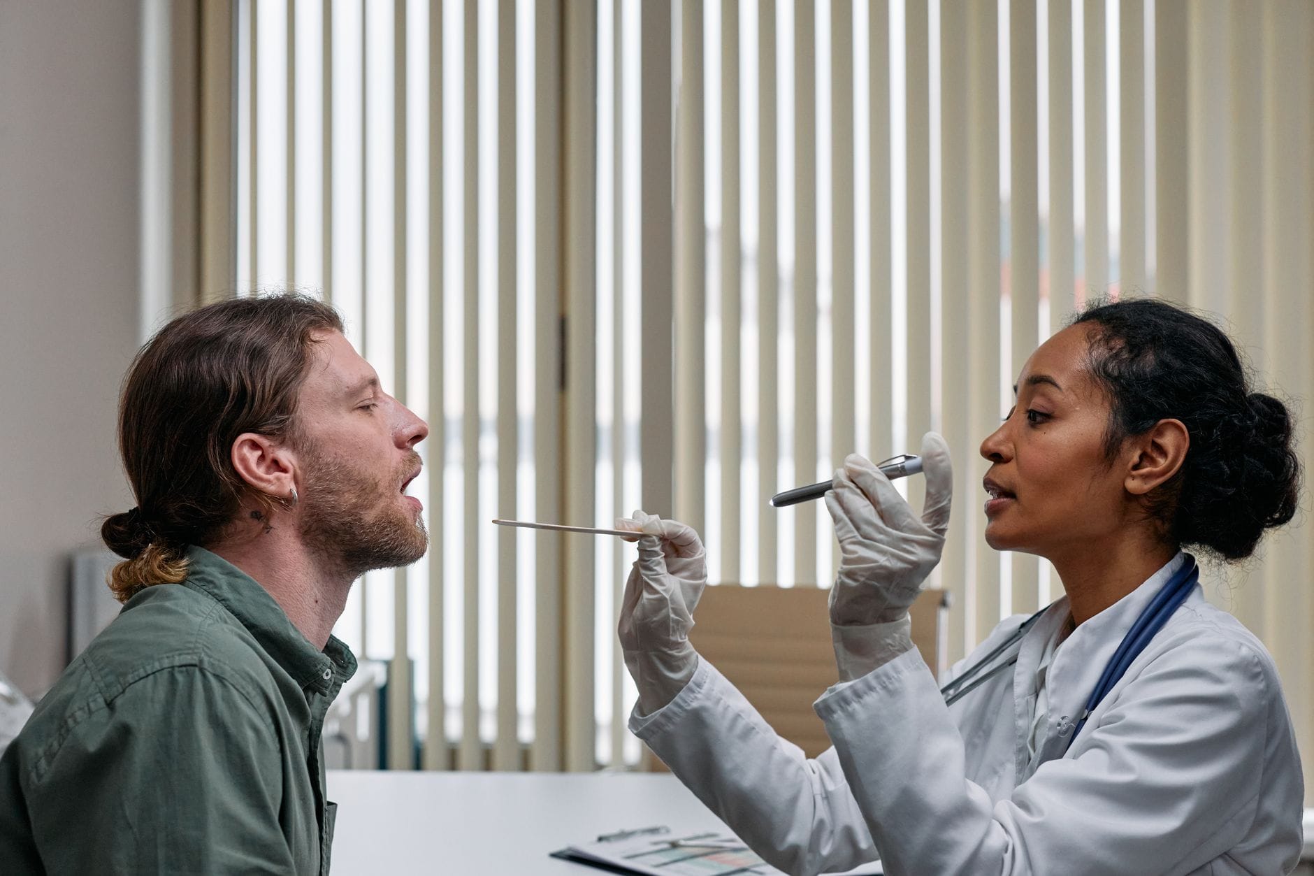 Doctor in white coat checking a seated patient's neck glands