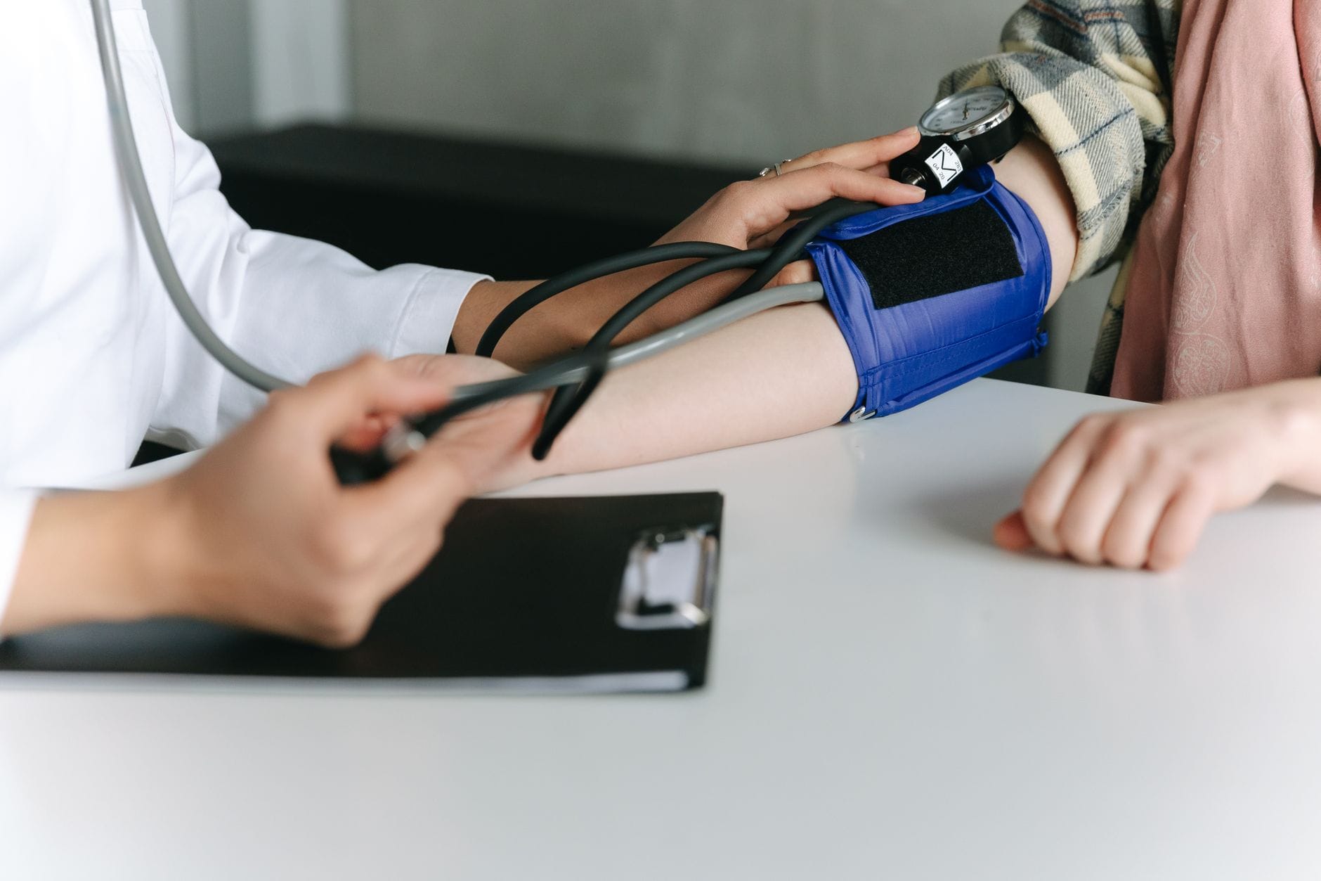A clinician wraps a blood pressure cuff around a patient's arm