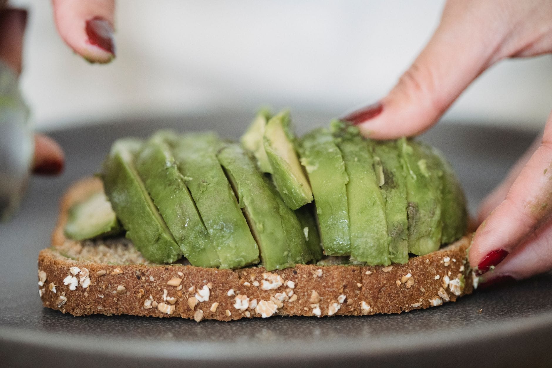 Sliced avocado spread on toasted bread beside fresh cherry tomatoes