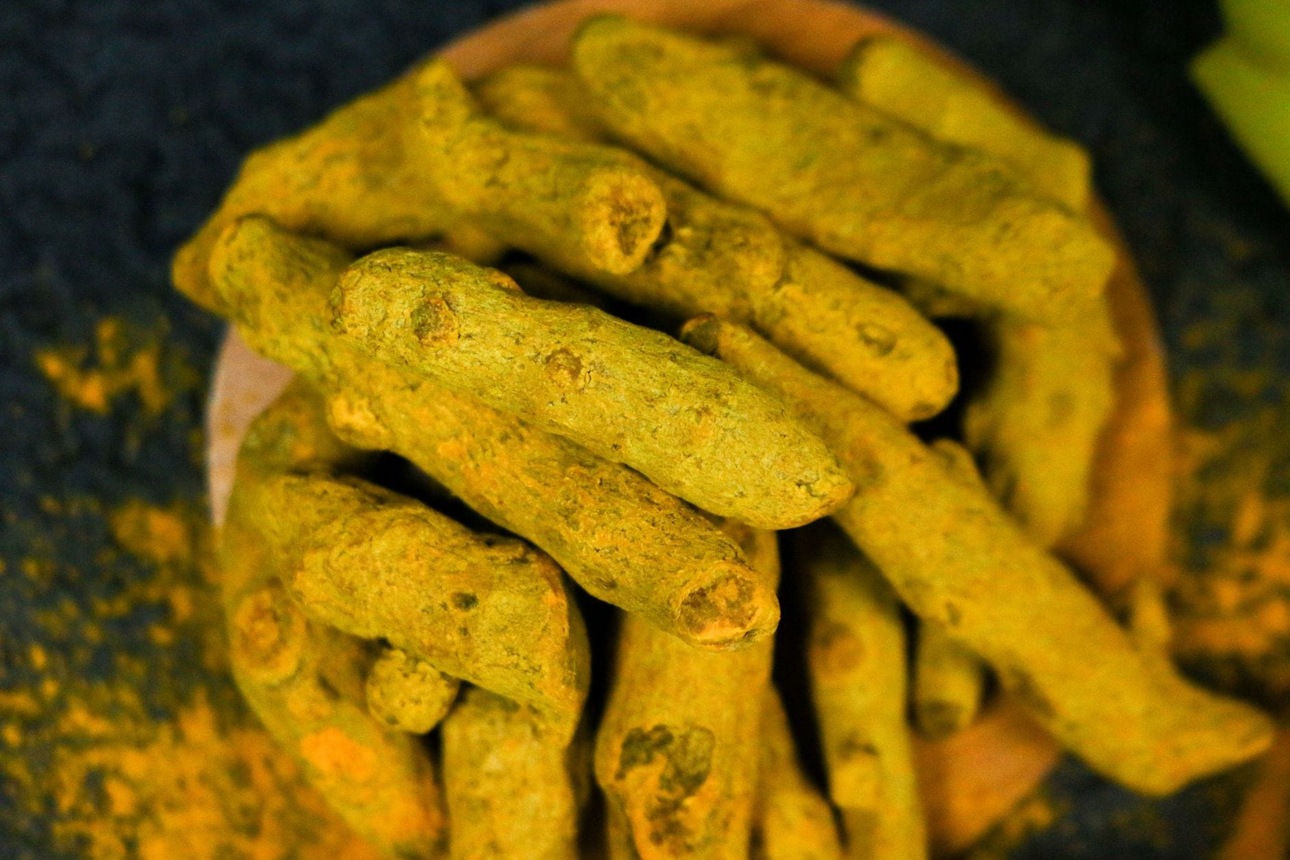 fresh turmeric roots and yellow powder on a wooden board
