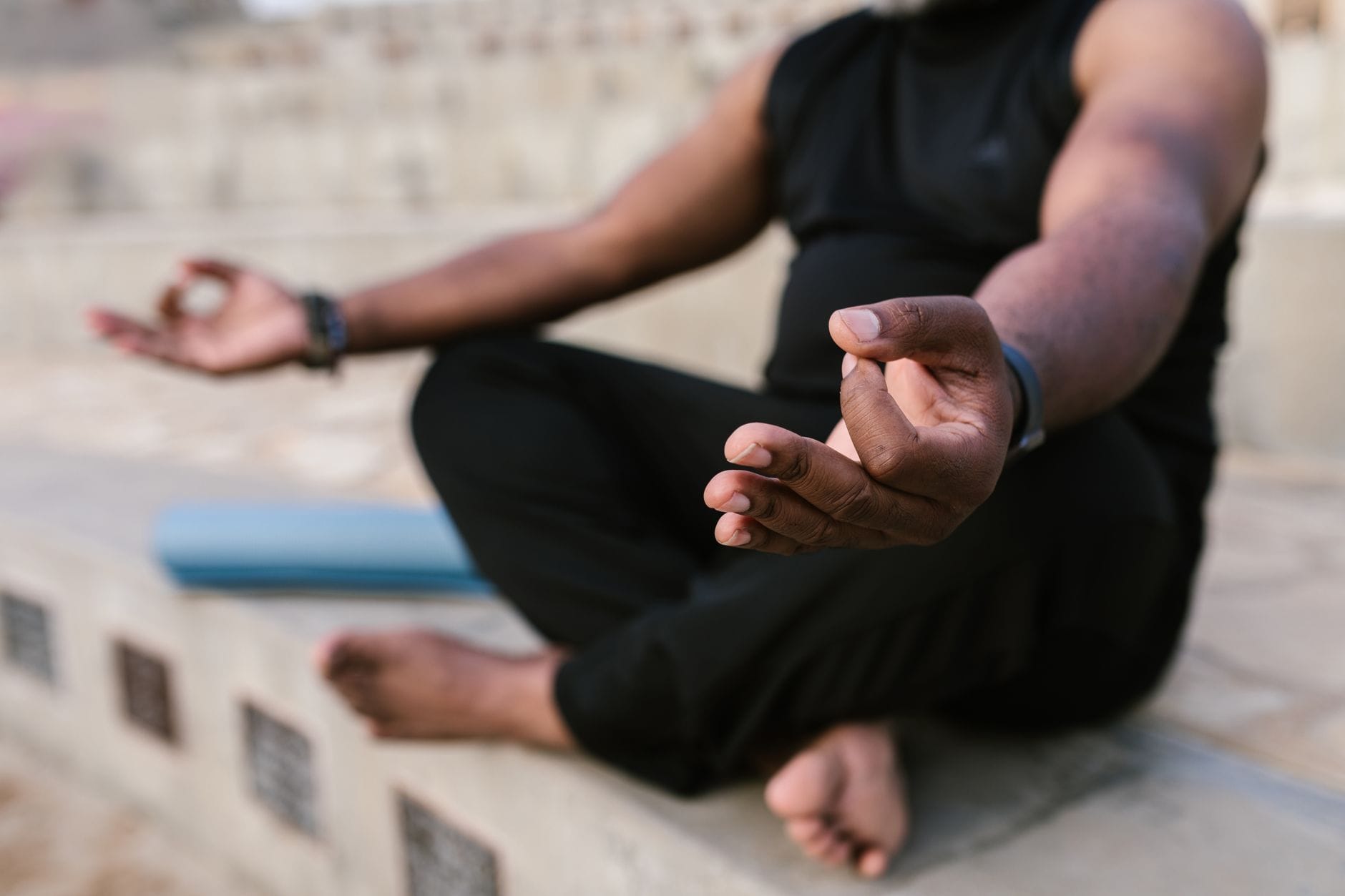 A woman sitting cross-legged meditating calmly on a mat in sunlight