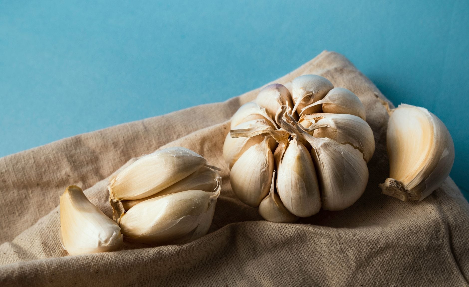 Peeled garlic cloves scattered beside a whole bulb on marble