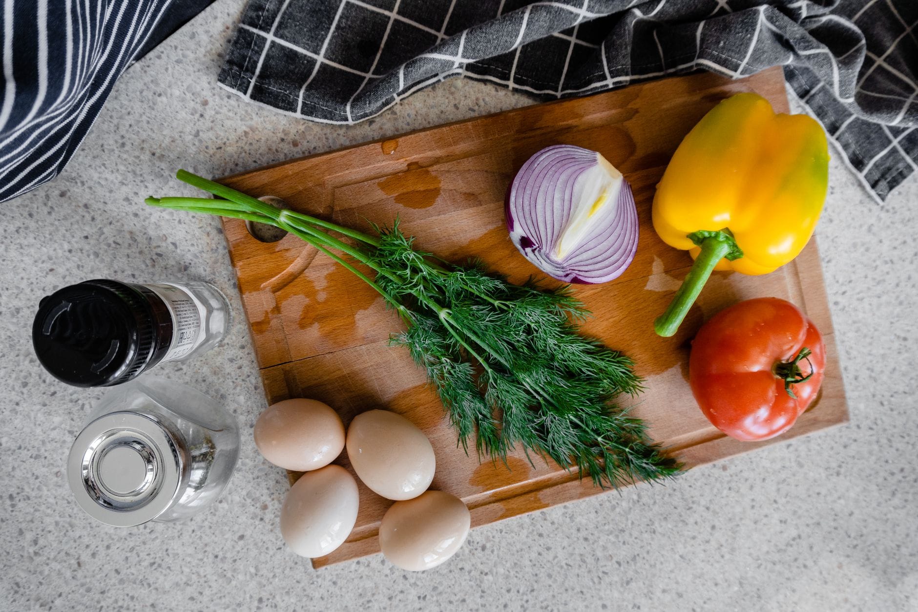 Colorful chopped vegetables on a cutting board beside a small salt shaker