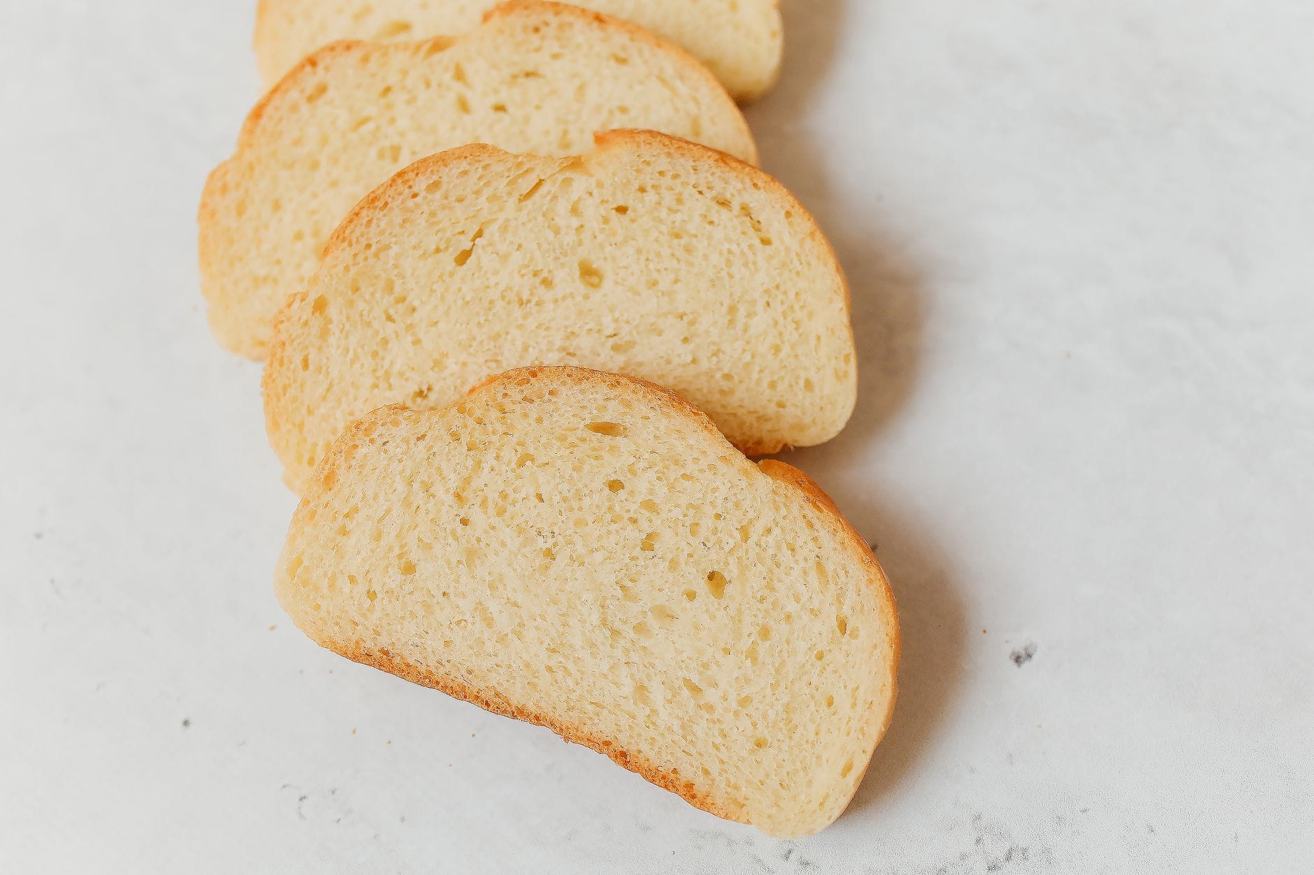 Stack of sliced white bread and pastries on a wooden board