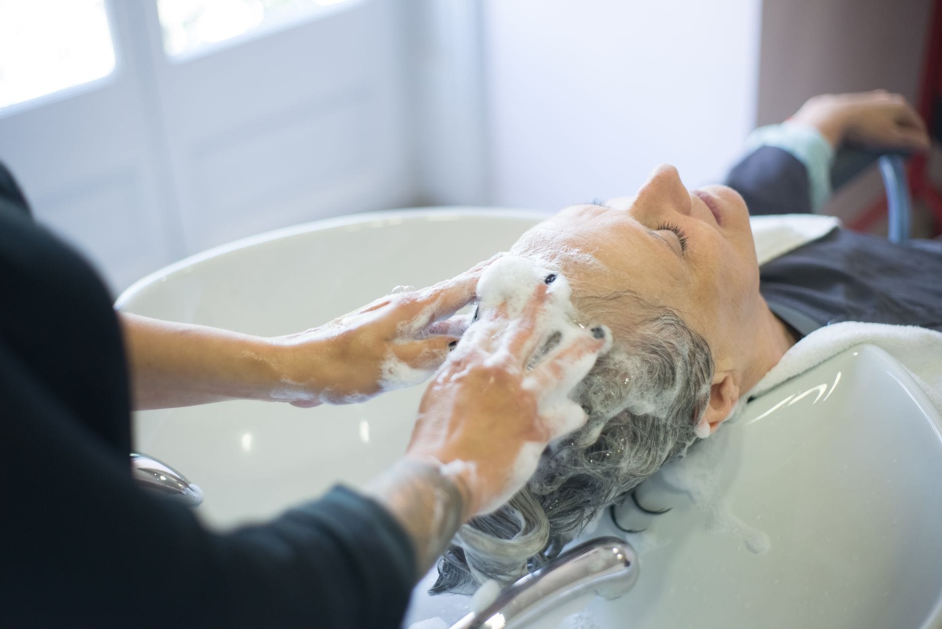 Woman massaging her scalp with fingertips while combing through long dark hair