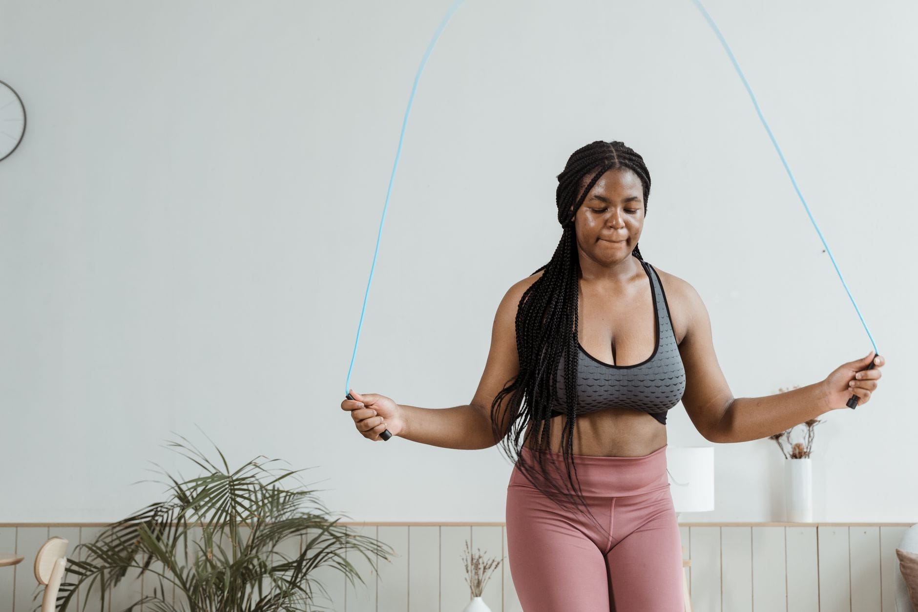 Woman mid-jump swinging a jump rope in a bright gym