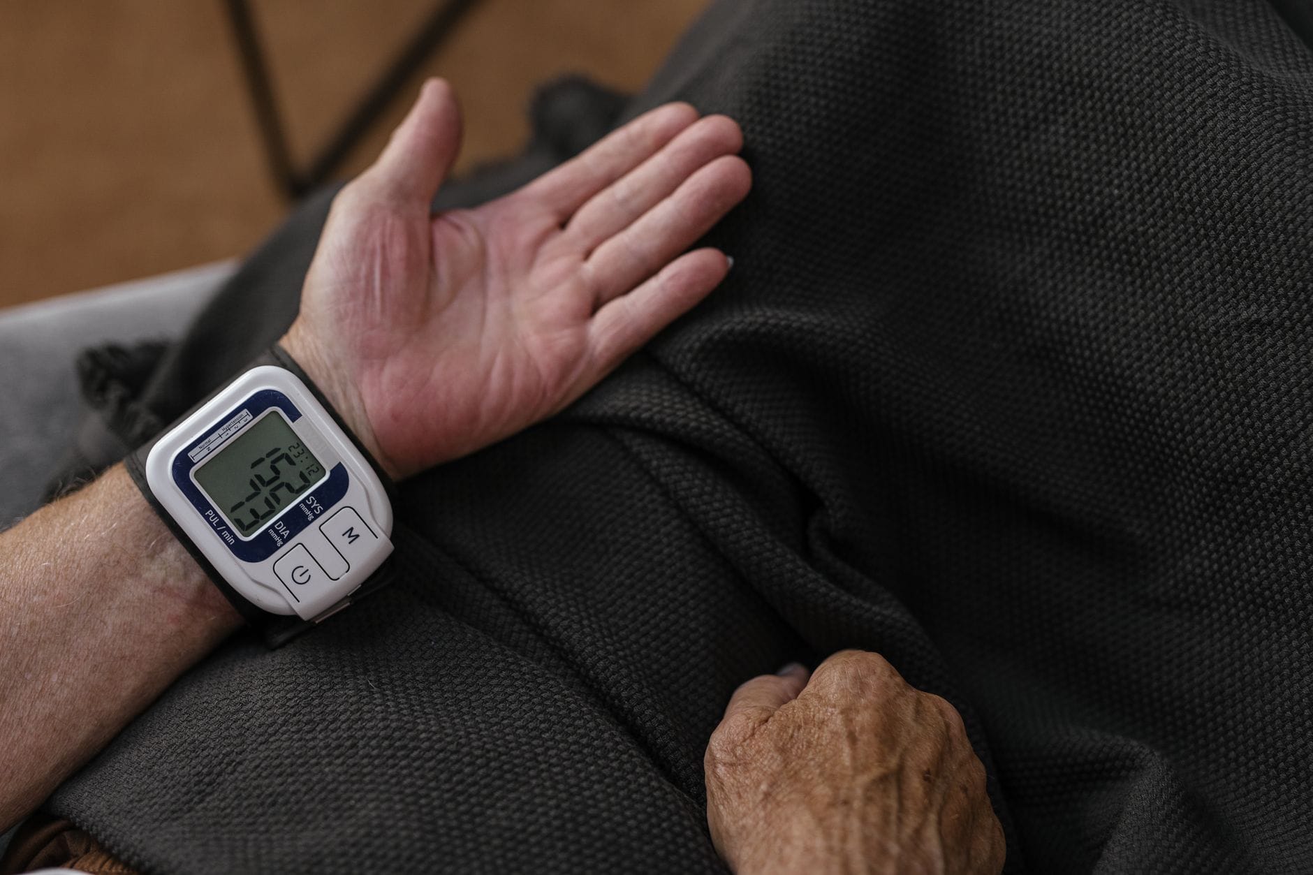 A woman wraps a blood pressure cuff around her upper arm