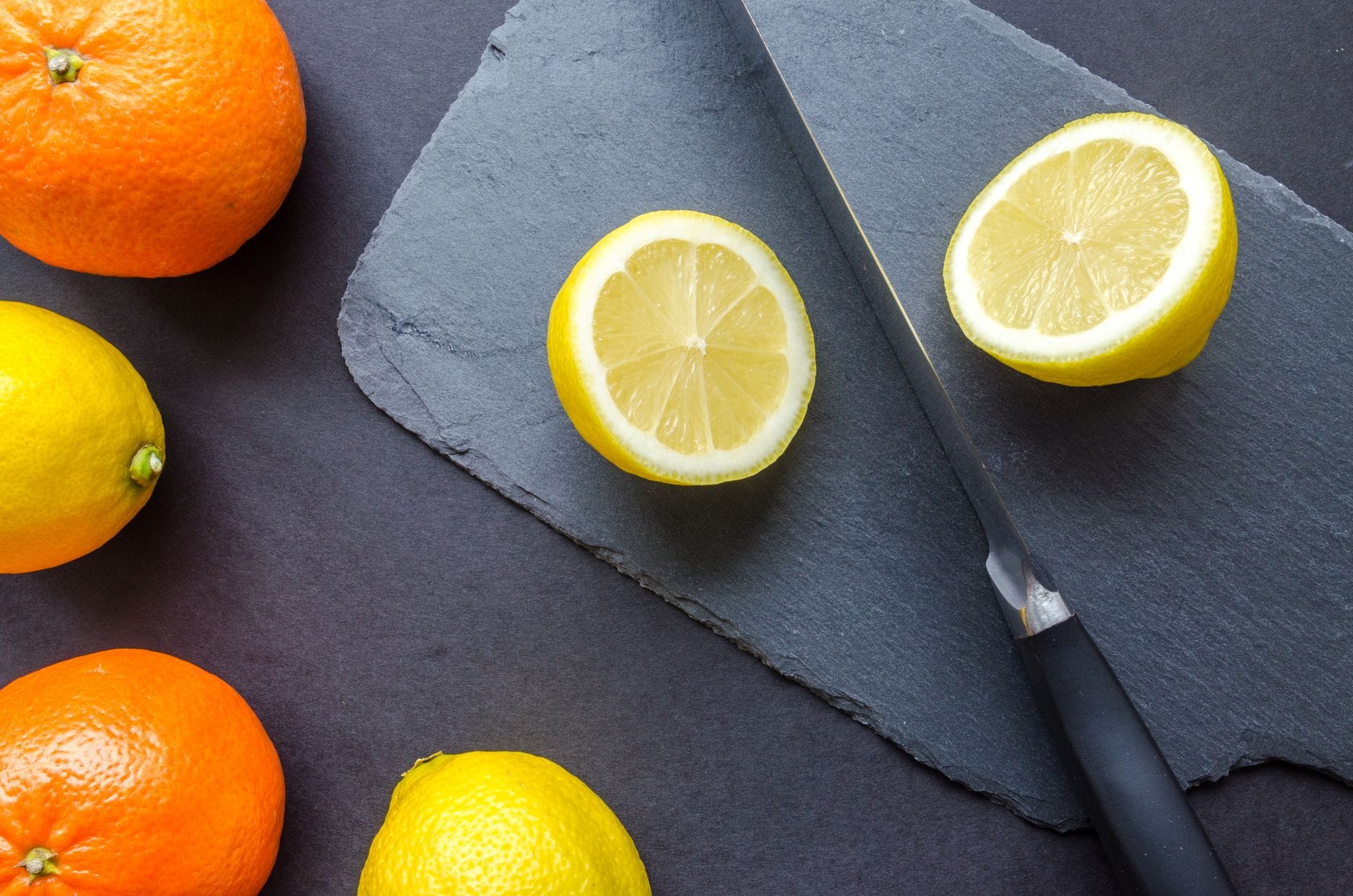 Halved fresh lemons and a small knife on a wooden cutting board