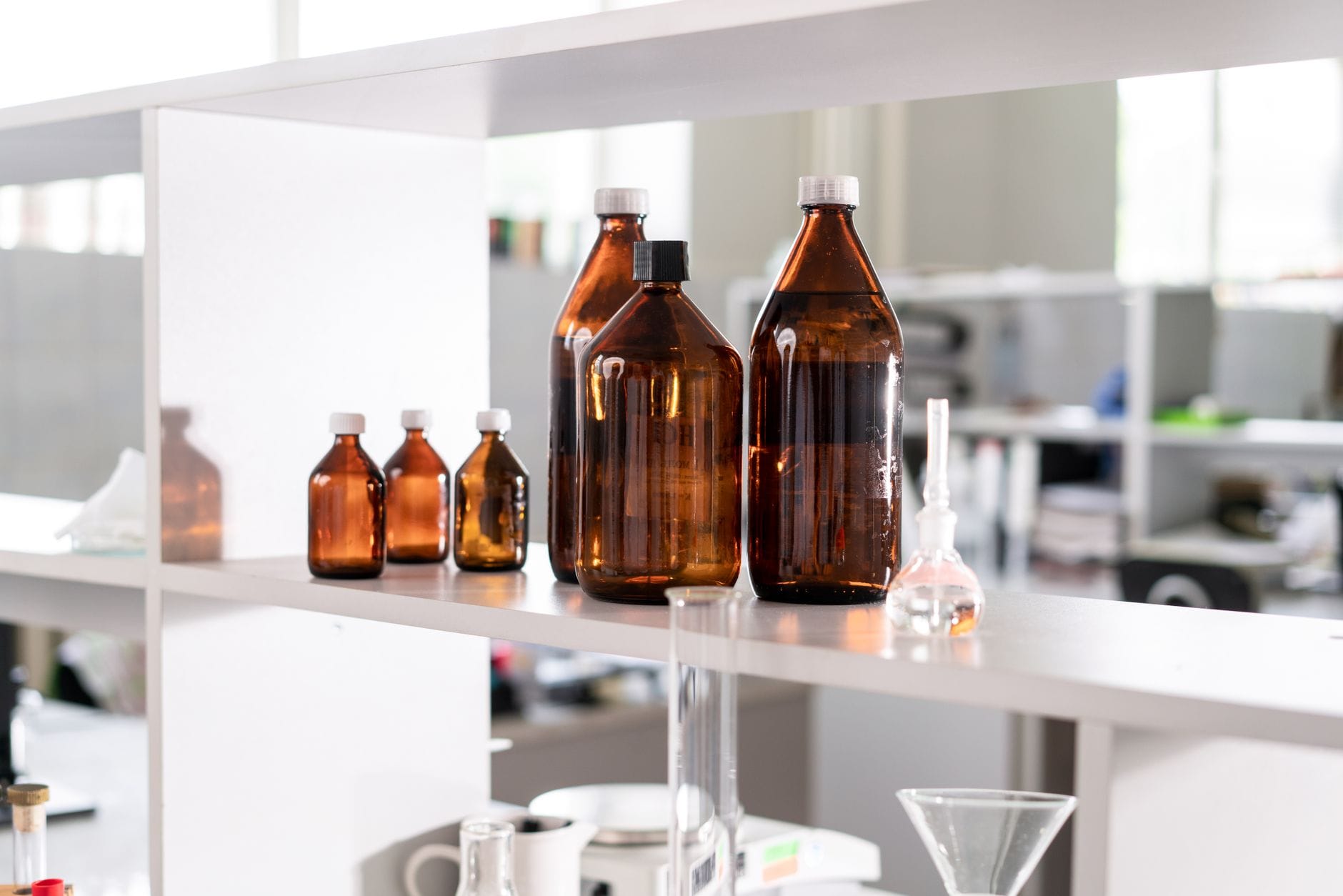 Small amber bottle of dark brown liquid beside a wooden spoon