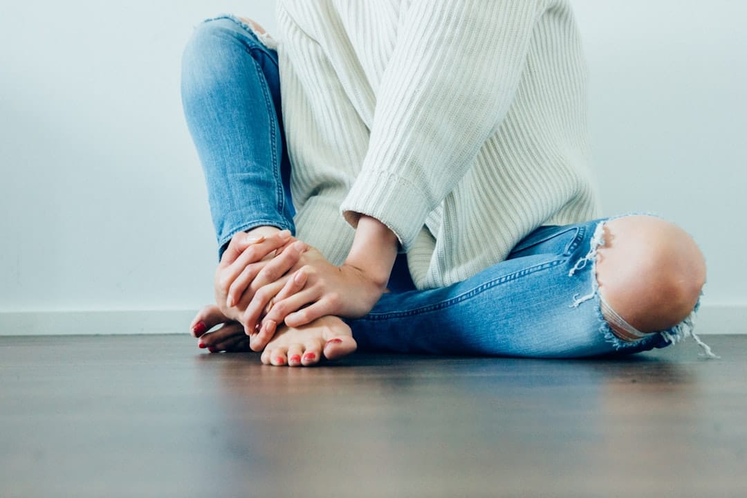A person seated on the ground gripping a swollen ankle after a fall