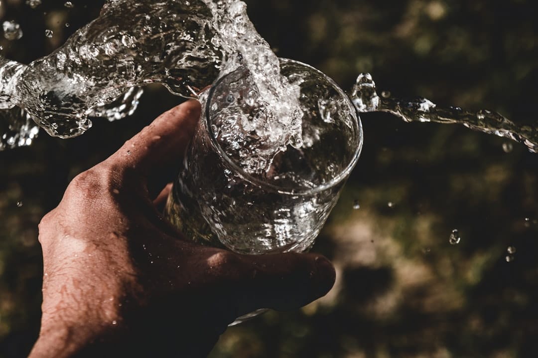 Clear water being poured into a tall glass on a bright kitchen counter