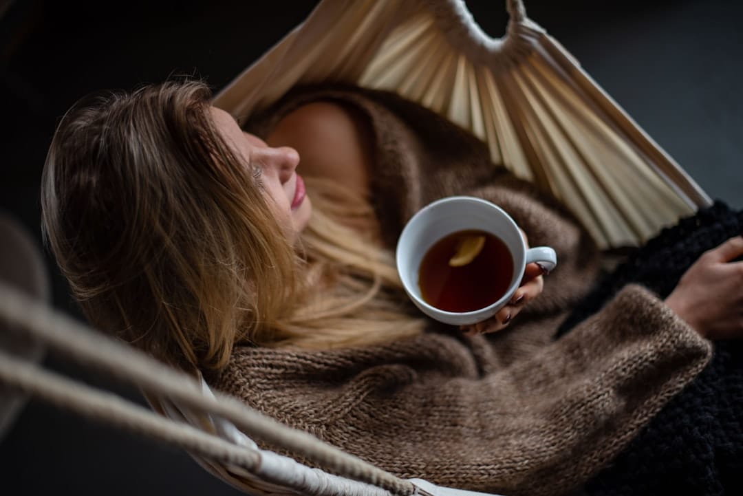 Person wrapped in a blanket cradling a warm mug of tea