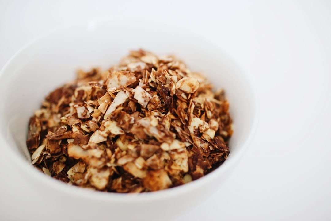 A wooden bowl of dry rolled oats on a kitchen table