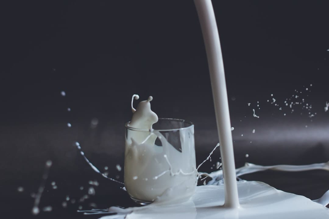 white milk being poured into a clear drinking glass