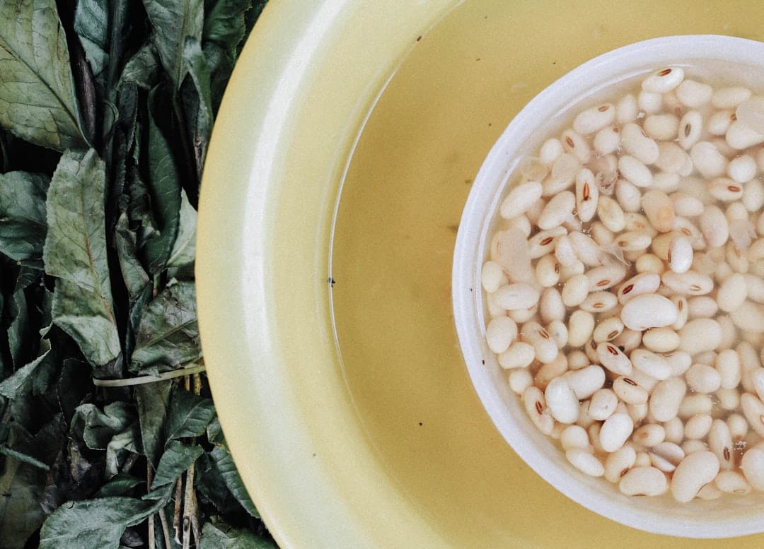 A pot of white bean and vegetable soup with a wooden spoon resting inside