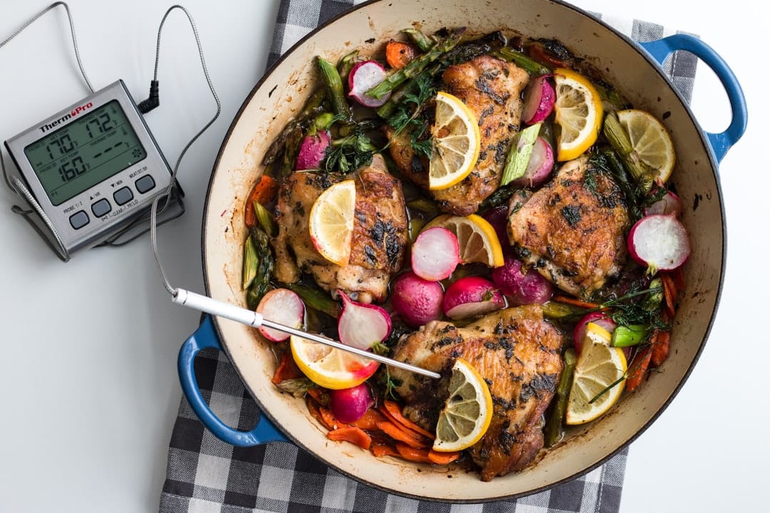 Digital thermometer inserted into a pork chop cooking in a pan