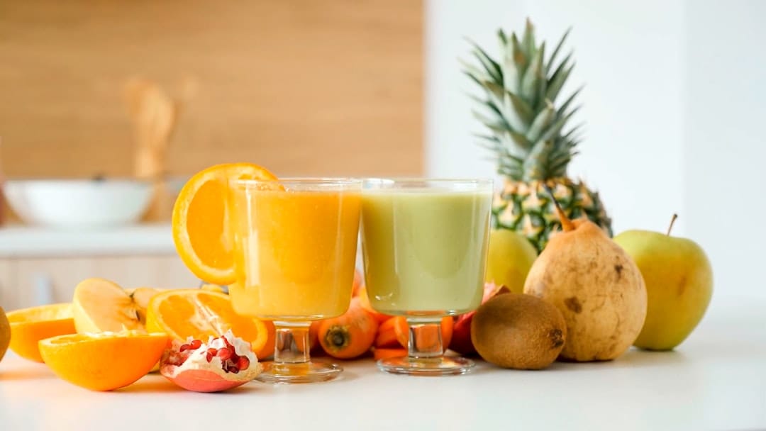 Tall glass of freshly blended orange juice with a straw and ice