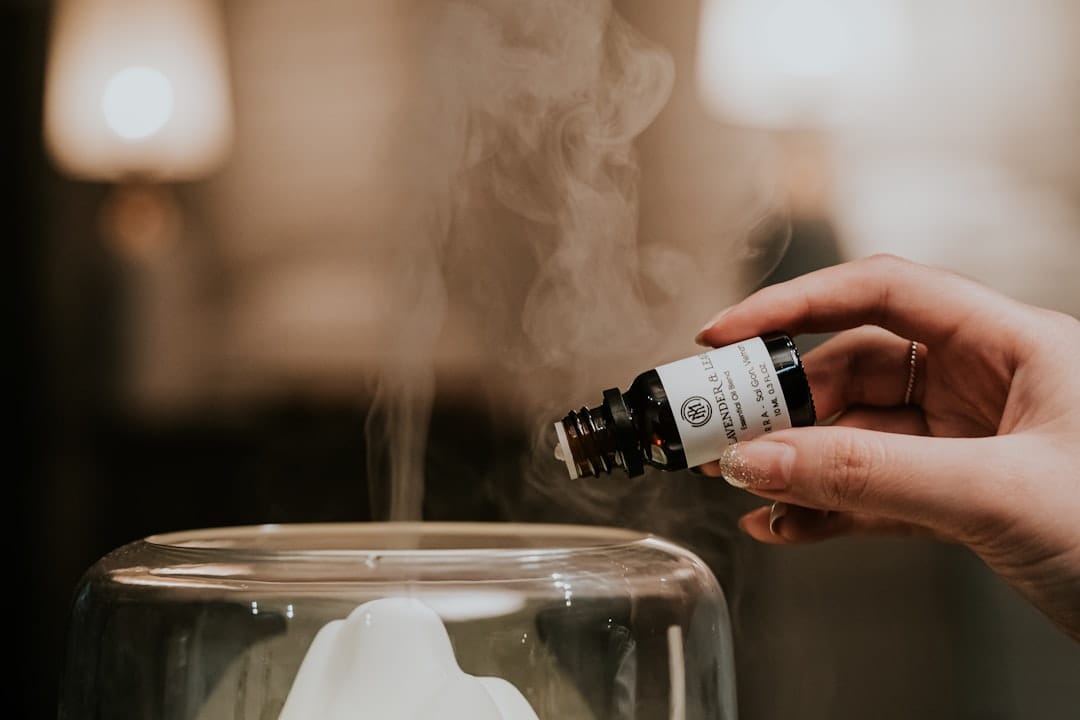 Ceramic aromatherapy diffuser releasing steam beside a small amber oil bottle