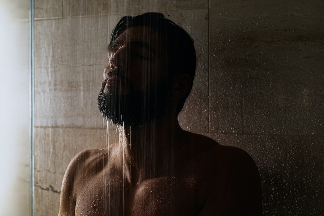 Close-up of soapy hands lathering shampoo into wet hair under running water