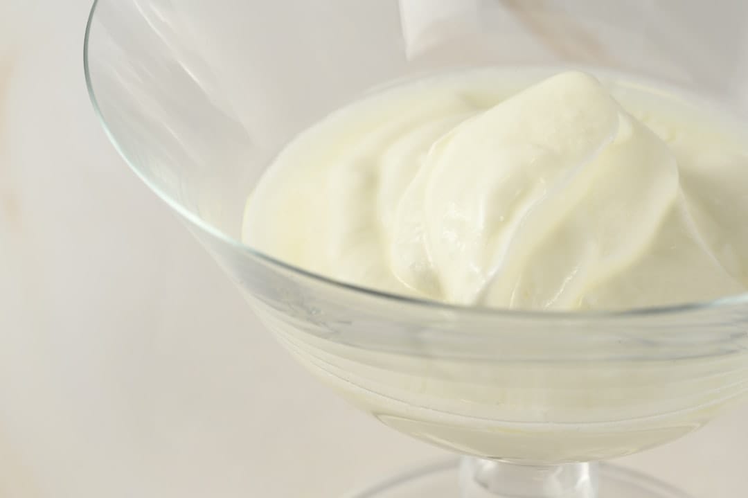 Wooden spoon dipping into a bowl of plain yogurt with berries