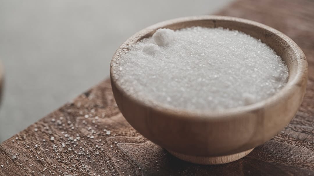 White Epsom salt crystals in a small glass bowl on a wooden surface