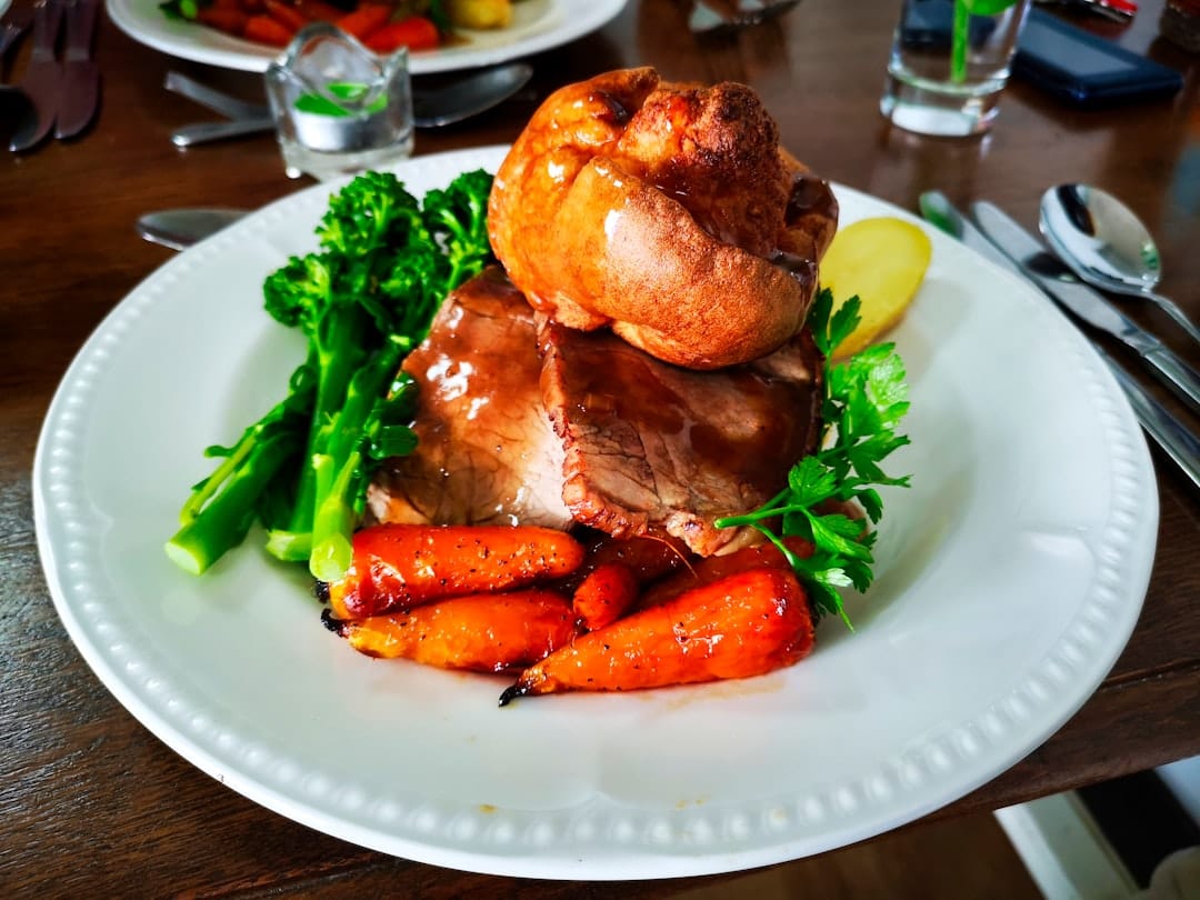 Sliced roasted pork tenderloin on a white plate with rosemary and vegetables
