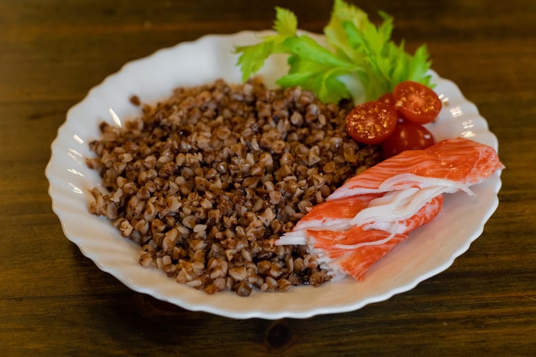 Raw triangular buckwheat groats piled in a rustic ceramic bowl