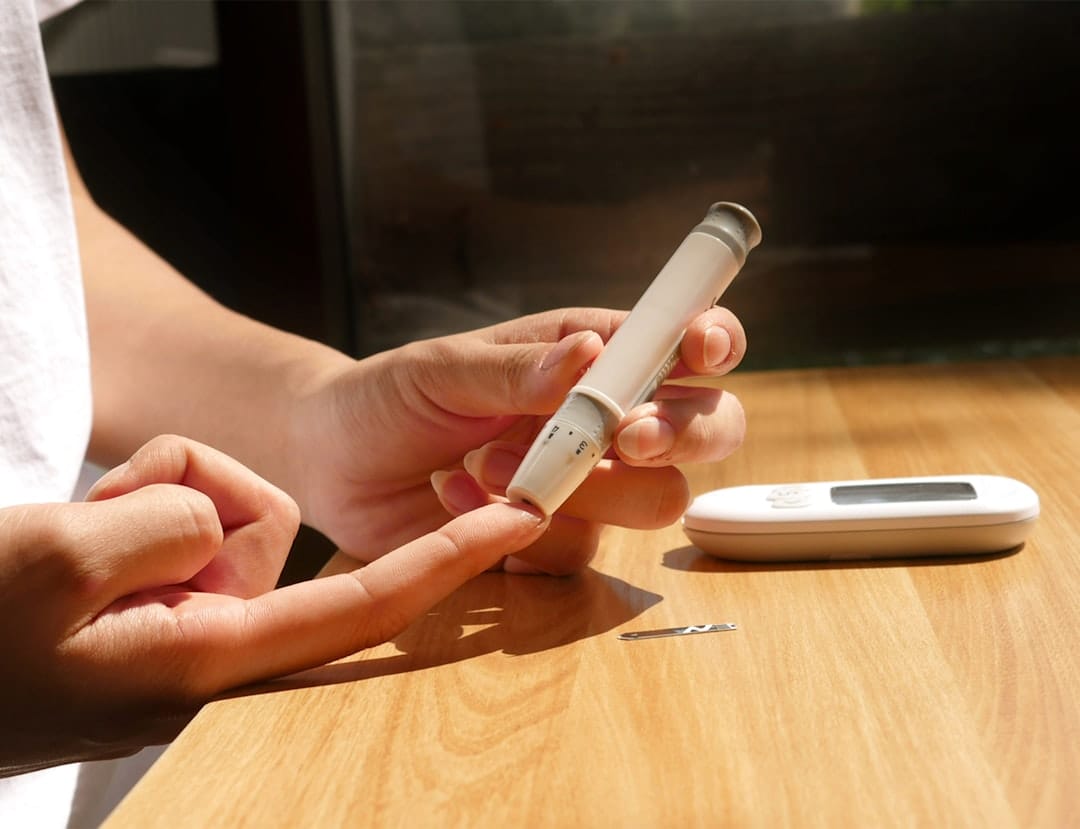 A person pricks a fingertip to check blood sugar with a glucose meter