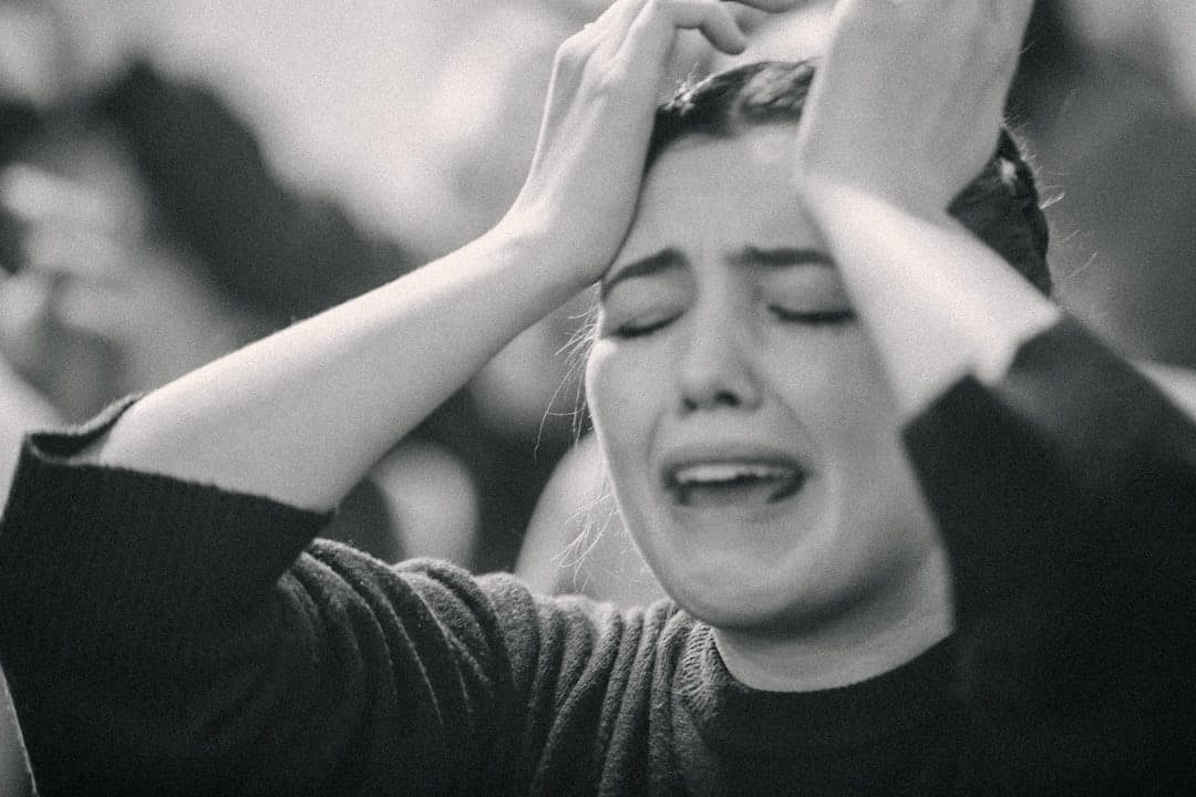 A woman wincing and pressing her fingertips to her temple in discomfort