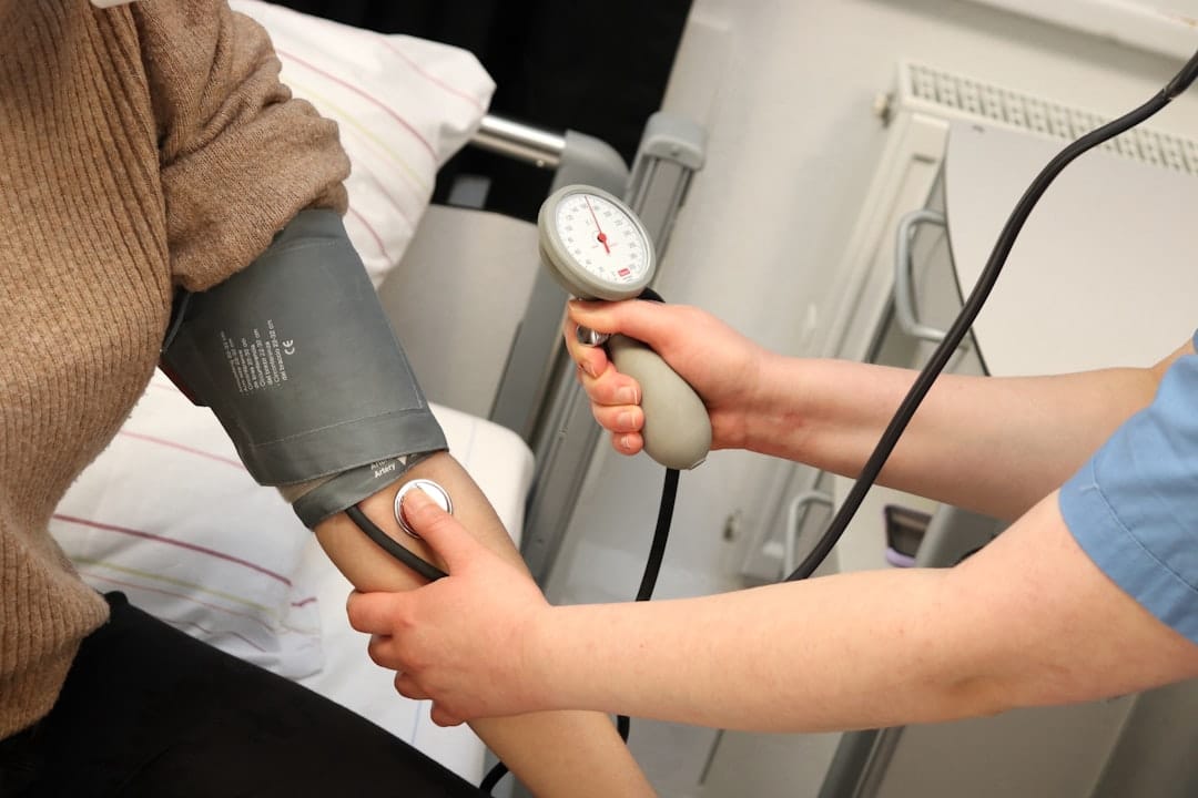 A clinician wraps a blood pressure cuff around a patient's upper arm