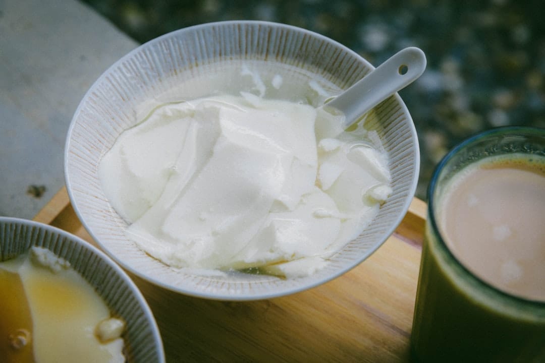 A white ceramic bowl filled with thick fresh curd on wood