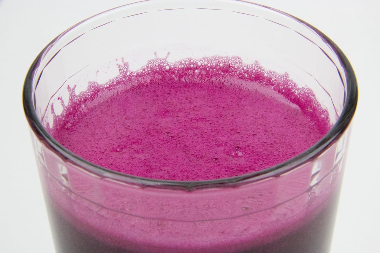 A glass of deep red beetroot juice on a light background