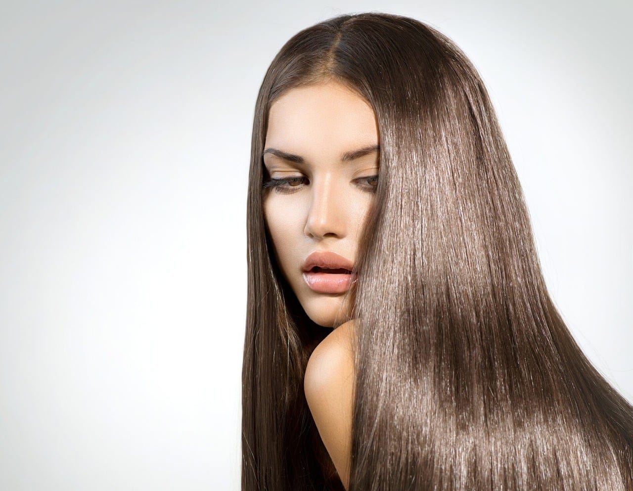 Woman running a brush through long, glossy dark hair