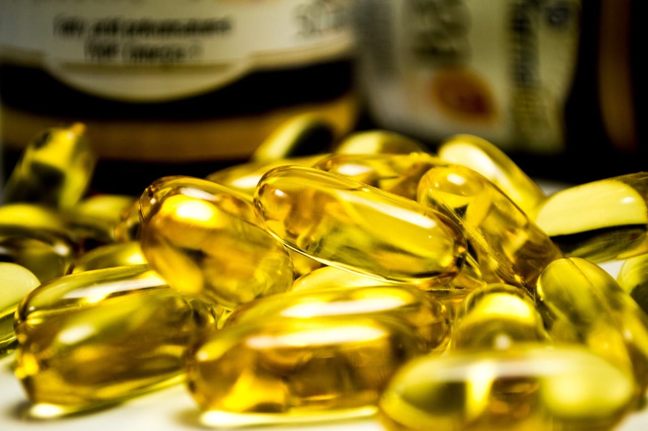 Amber softgel capsules spilling from an open supplement bottle
