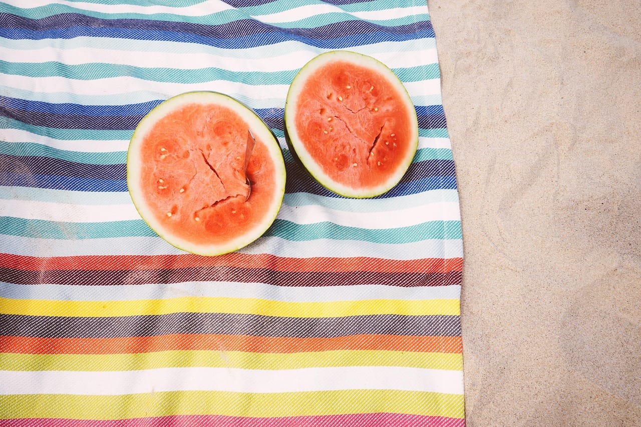 A whole watermelon cut in half showing bright red flesh and dark seeds