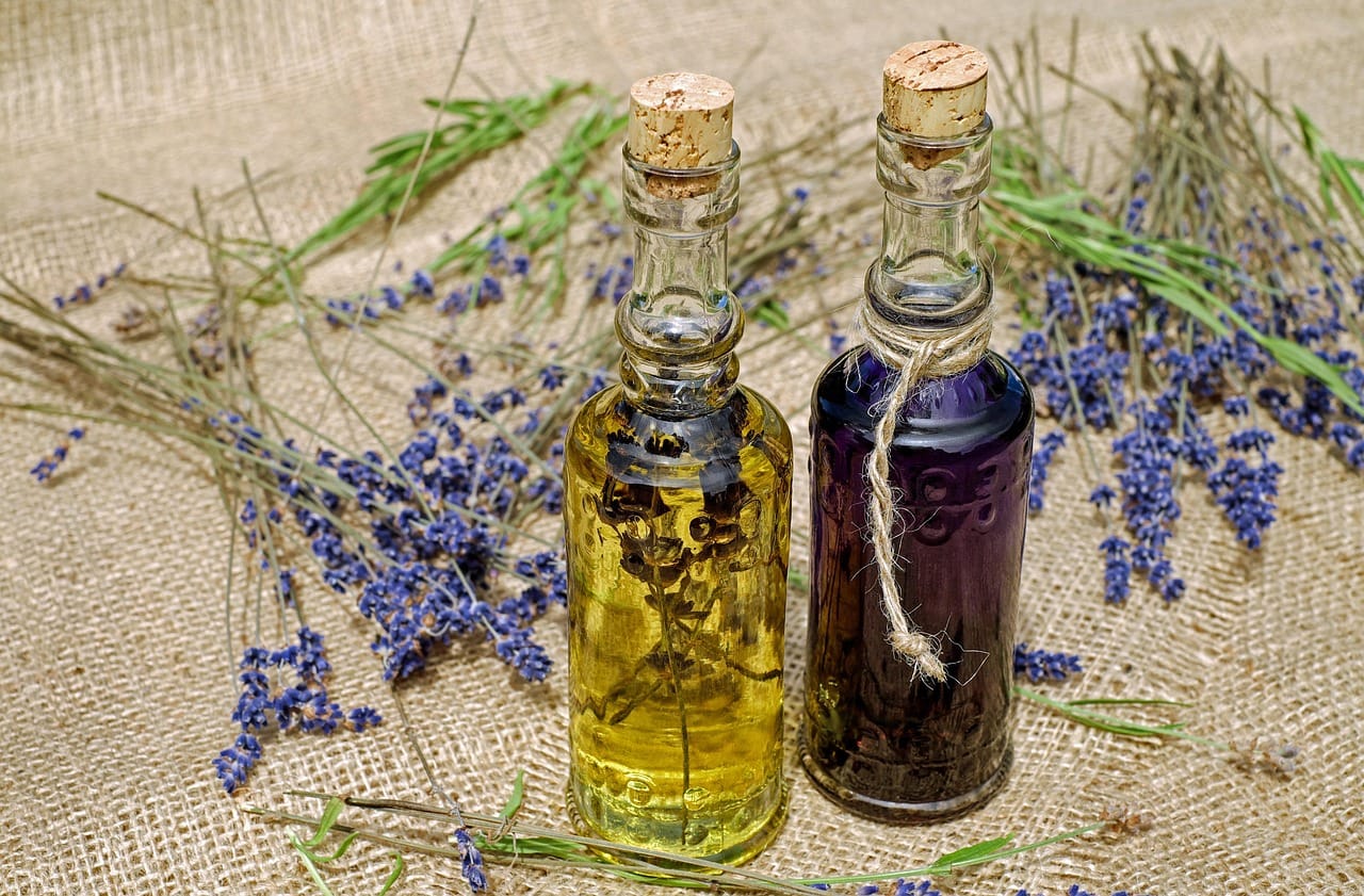 Hands parting dark hair to massage oil into the scalp