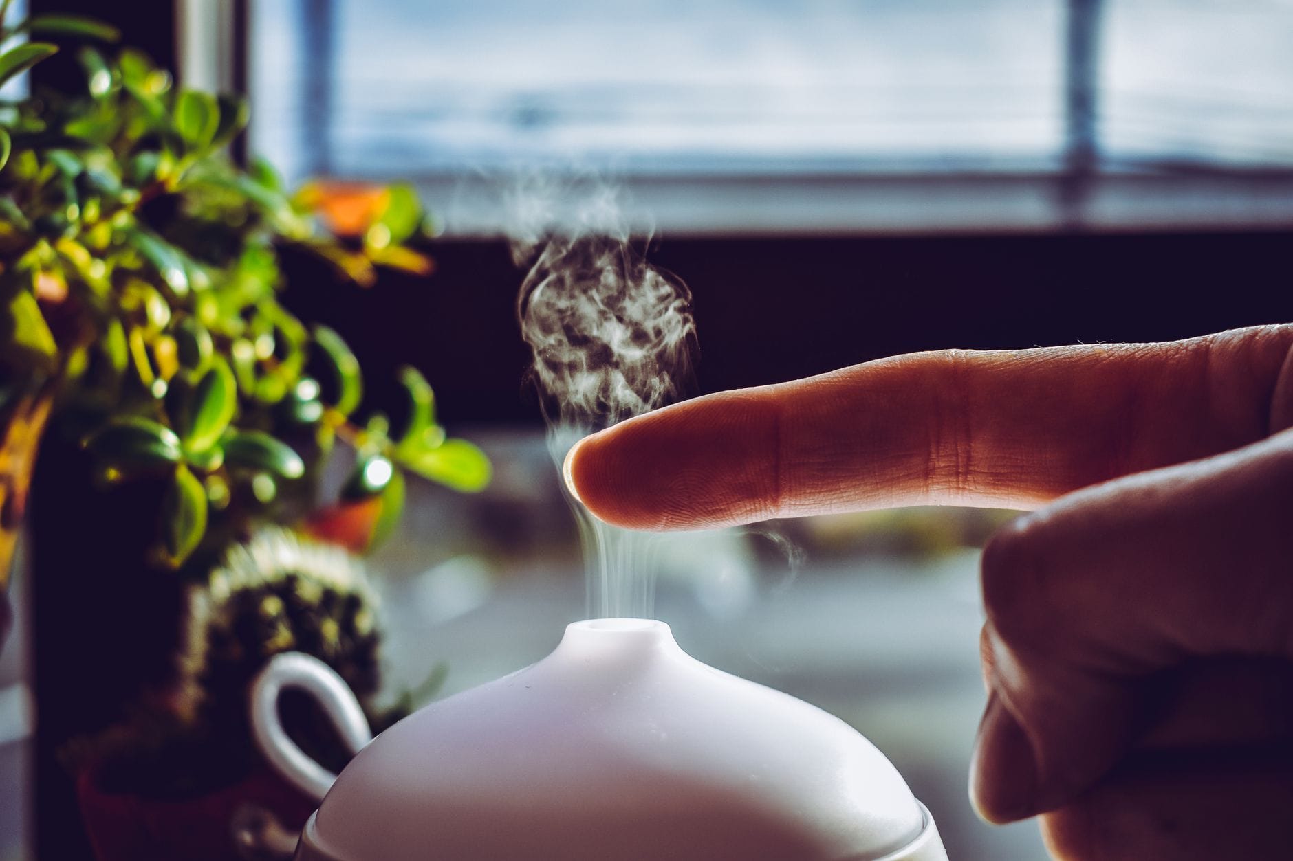 Woman resting on a couch near a steaming essential oil diffuser