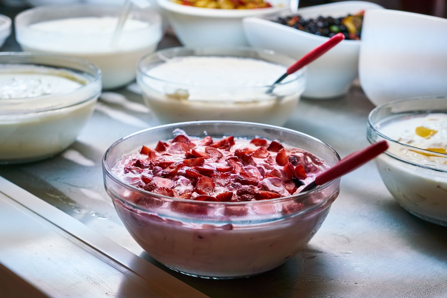 Bowl of thick white face mask beside a wooden spoon and fresh lemon