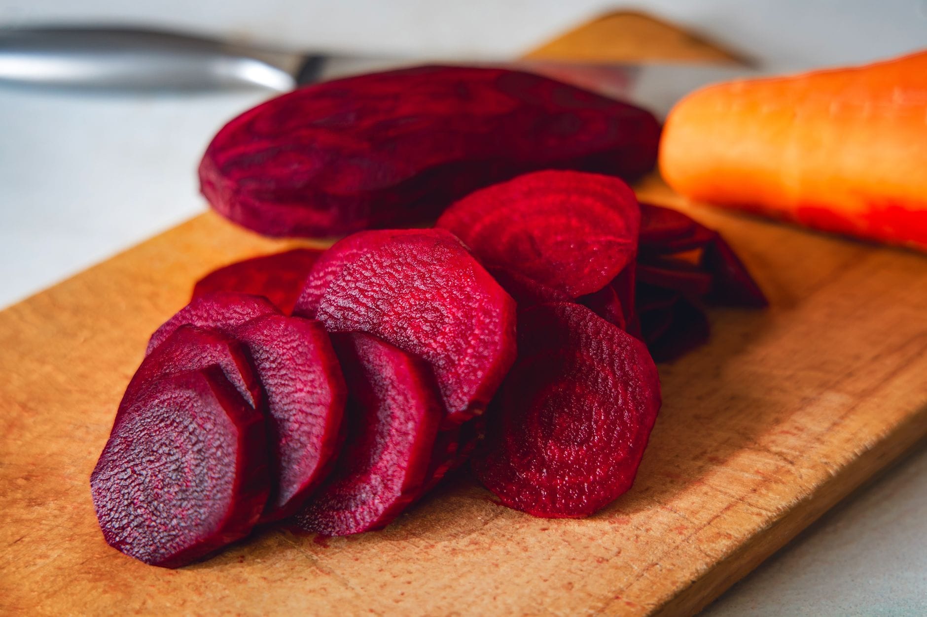 Sliced raw beetroot showing deep red rings on a wooden board