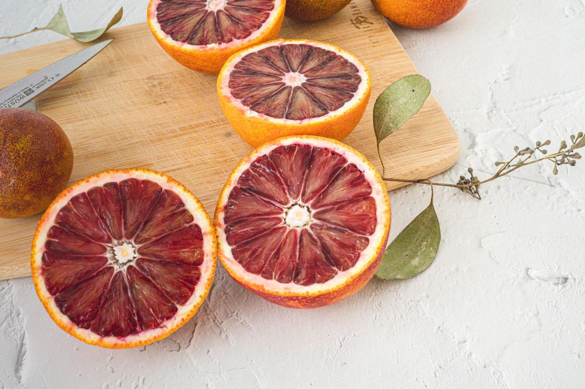Halved blood oranges showing deep crimson flesh on a marble surface