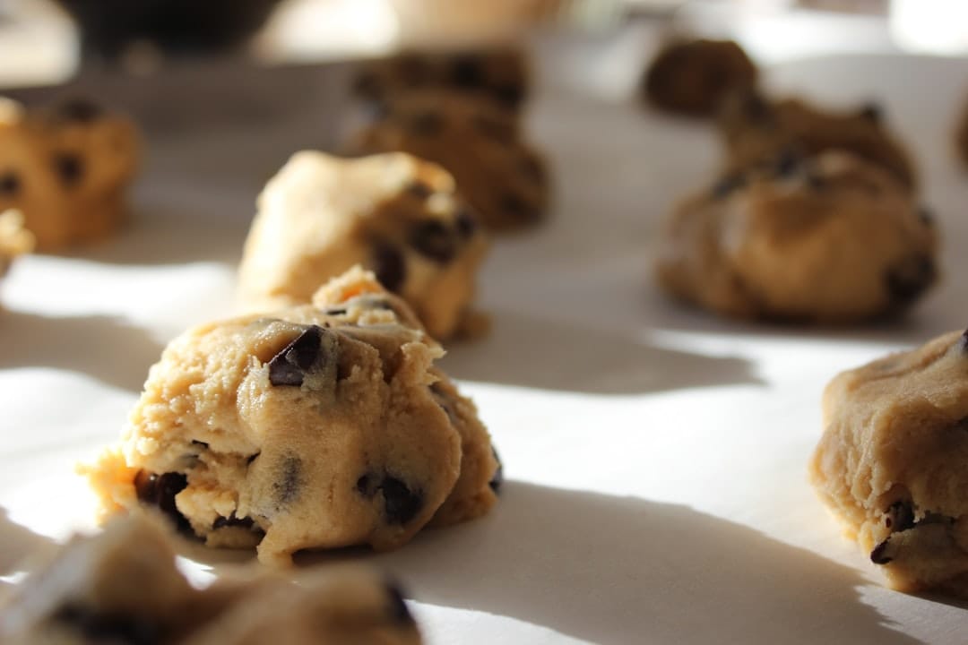 Balls of cookie dough spaced on a lined baking sheet