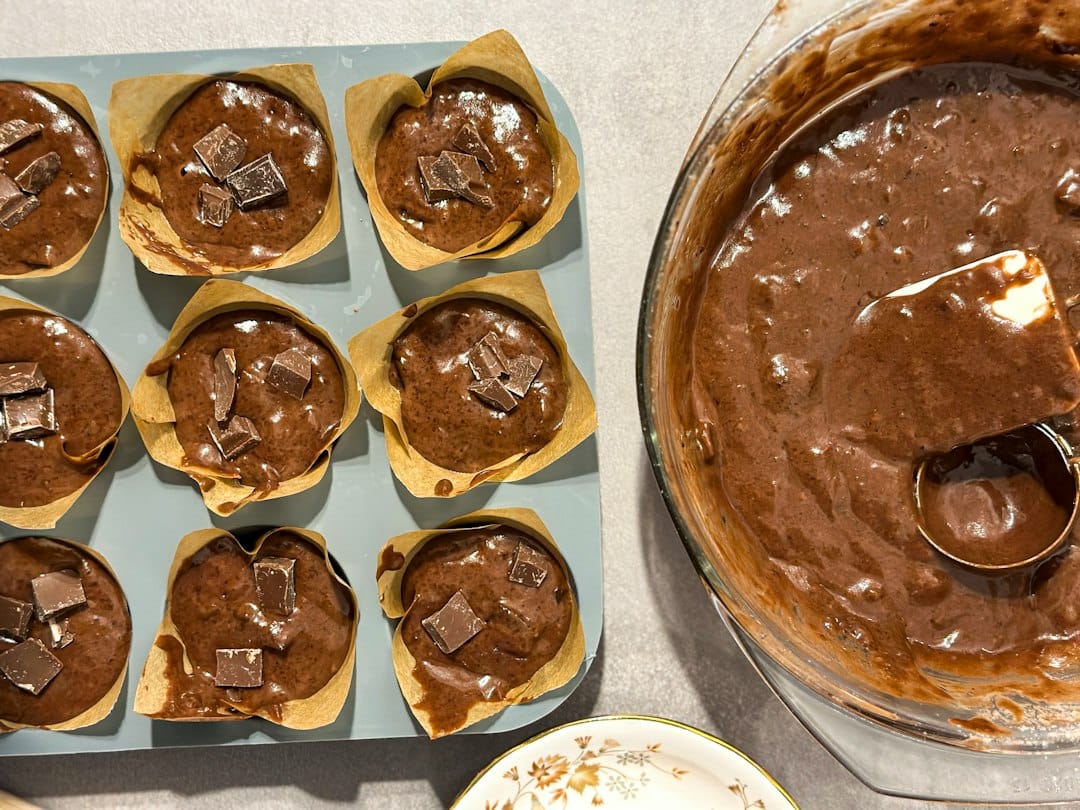 Orange muffin batter portioned into a lined muffin tin